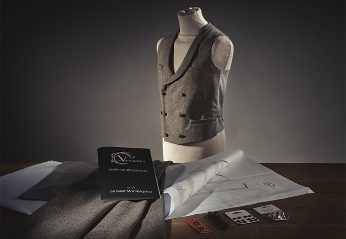 Kit de création de gilet, avec le livret de réalisation, le patron et les accessoires étalés sur une table, et le gilet assemblé sur un mannequin.