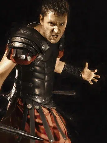 Homme armé habillé en soldat romain, équipé d'une tunique rouge, ainsi qu'une armure, une jupe et des avant-bras en cuirs.